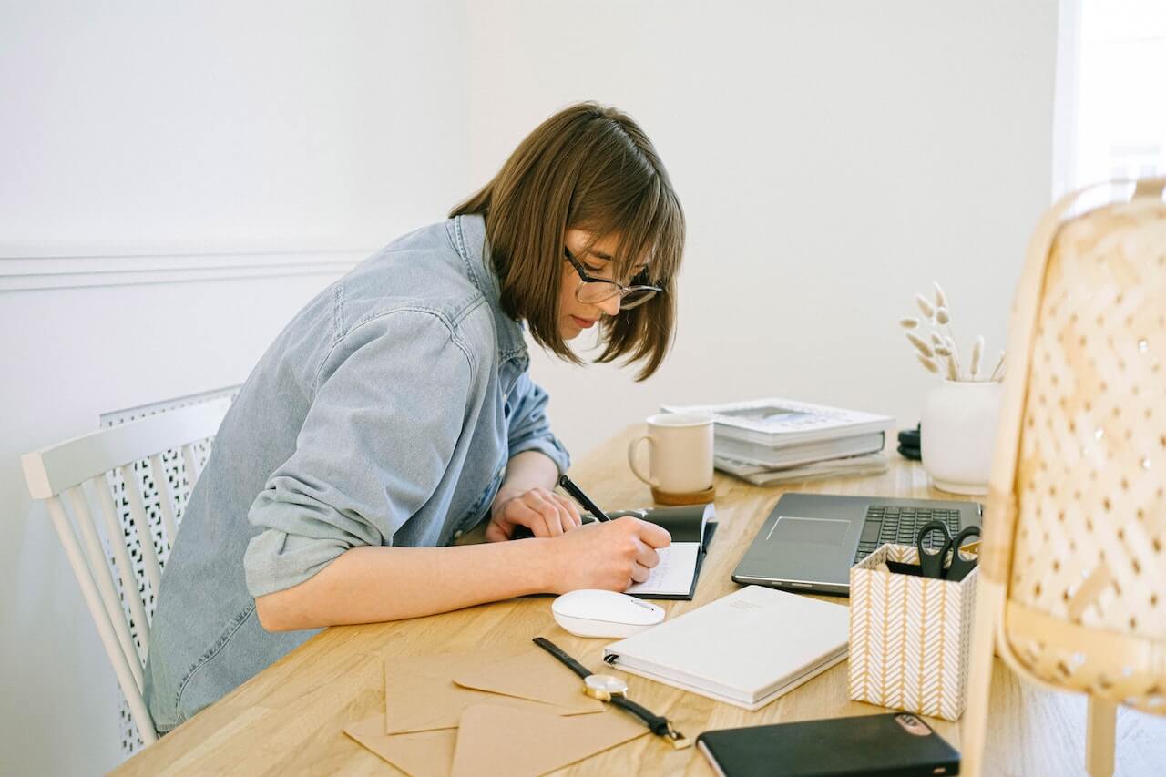 A woman filling out paperwork on a busy desk