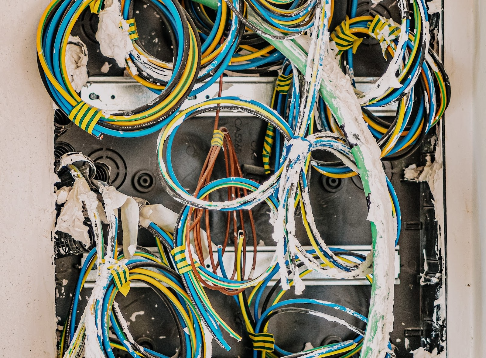 a number of coloured electrical wires inside a wall