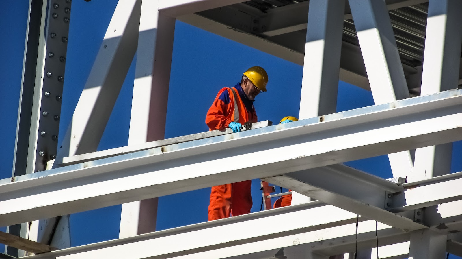 A builder in orange high visibility clothes a top a white building