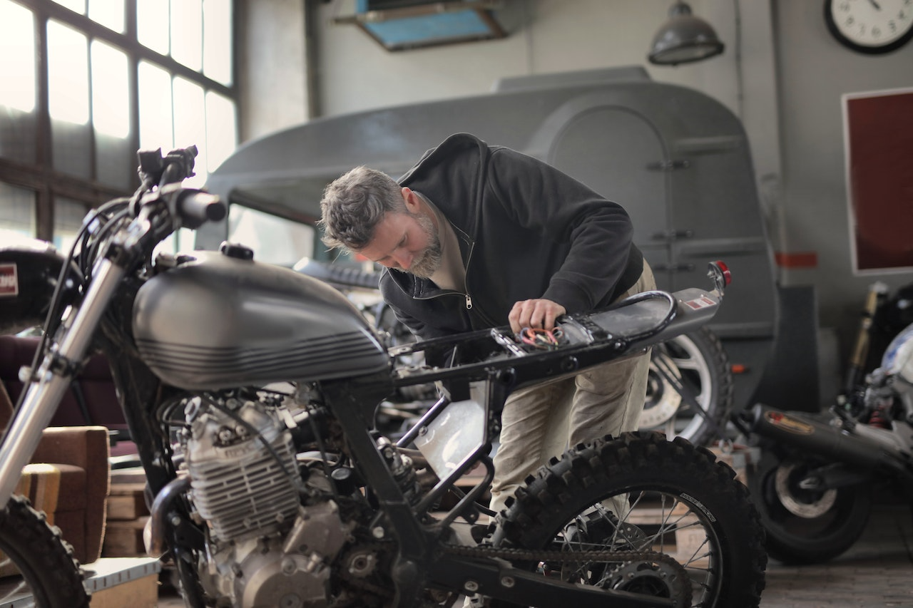 Man fixing his motorbike in a garage