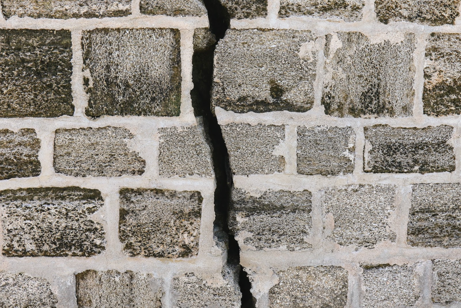 a deeply cracked grey brick wall