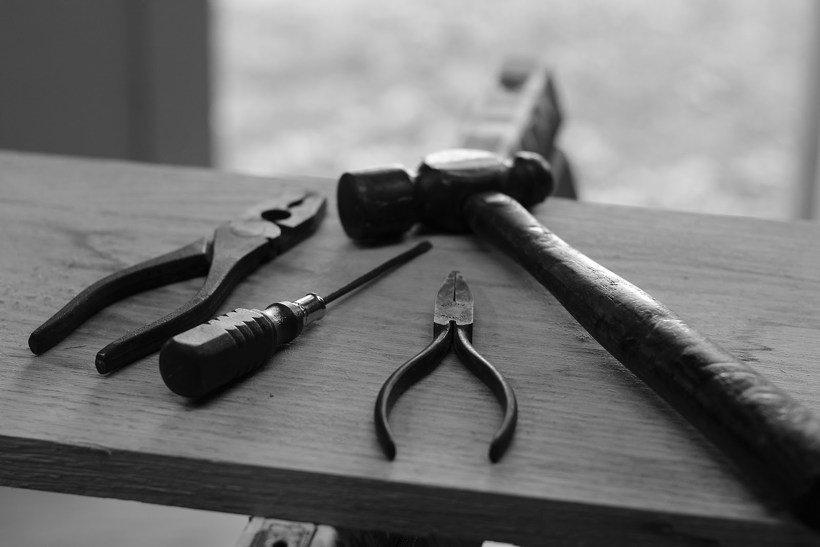 black and white photo of an assortment of tools on a plank of wood