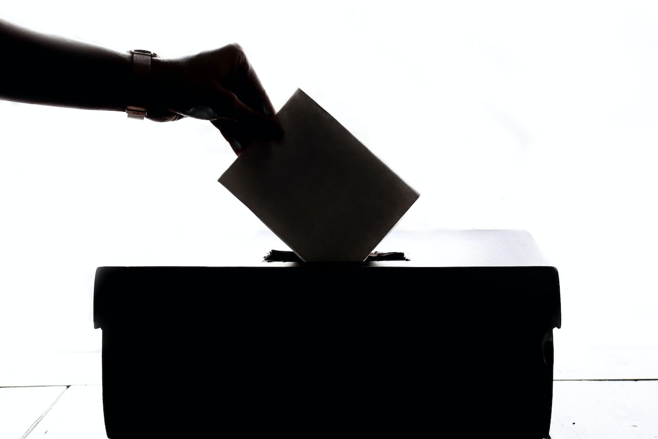 A silhouette of someone putting their ballot paper in the ballot box