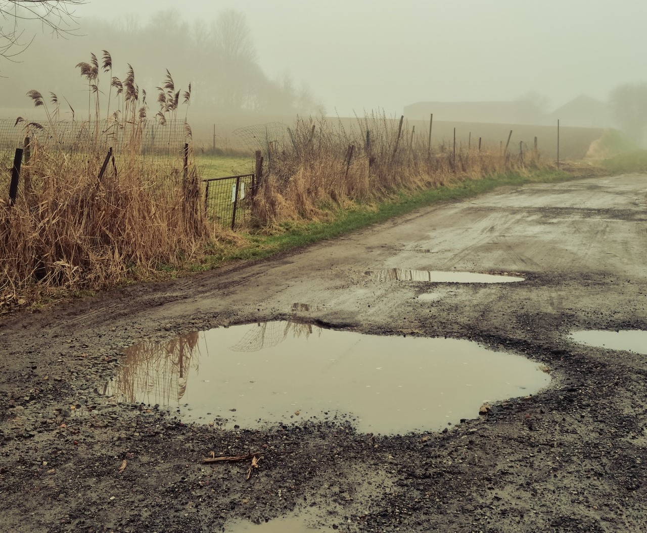 A puddle in a large pothole on a country road