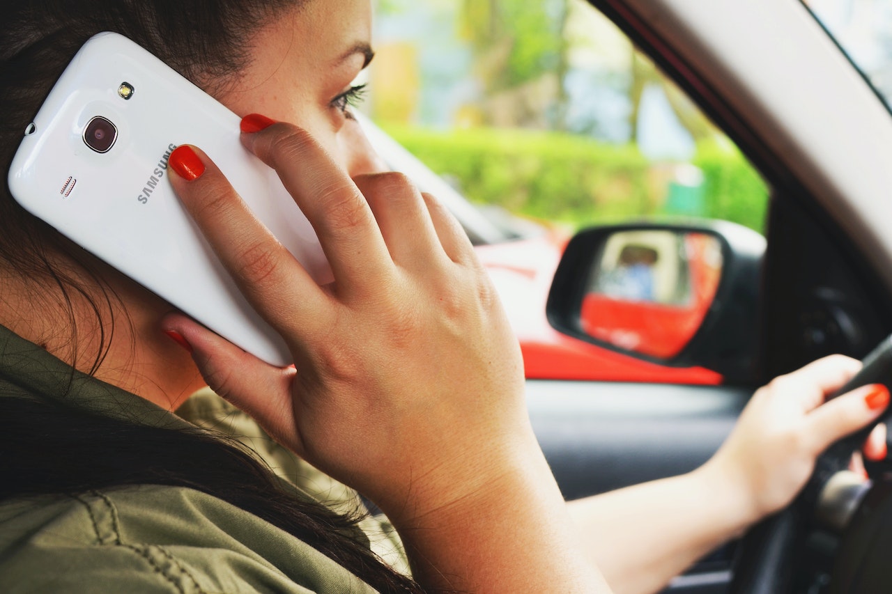 woman driving car while speaking on phone