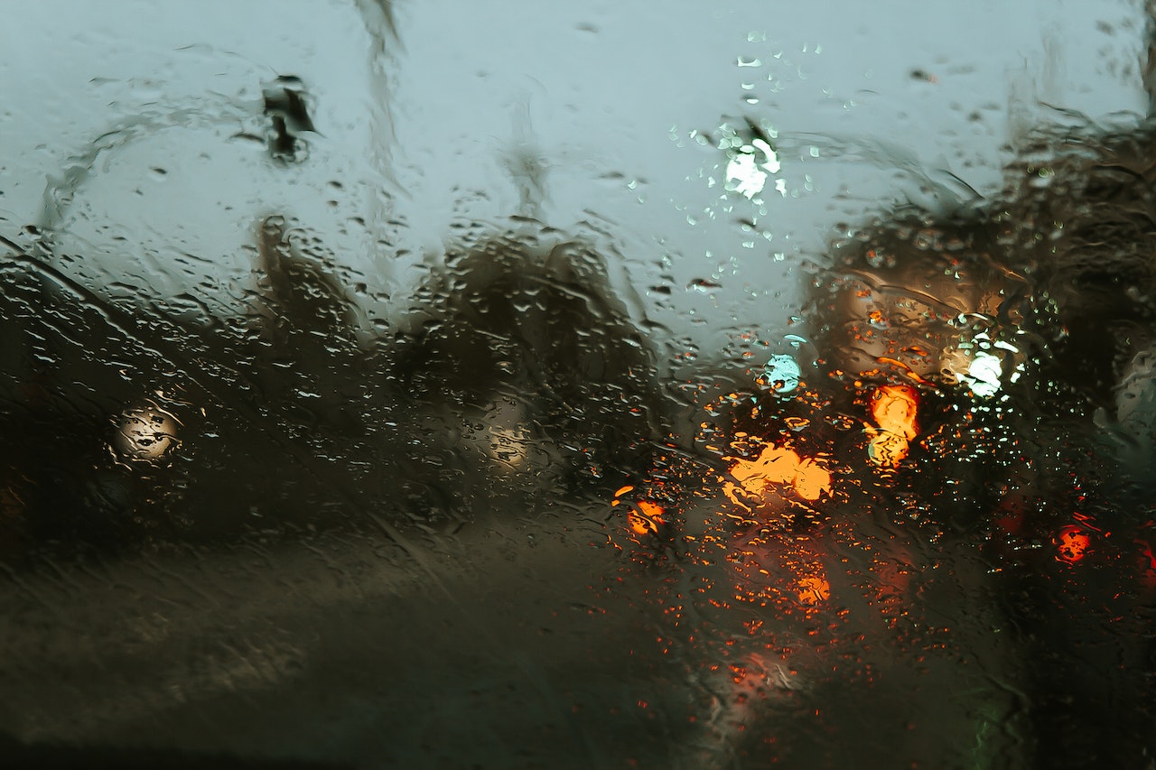looking through a rainy windscreen mirror onto a crossing