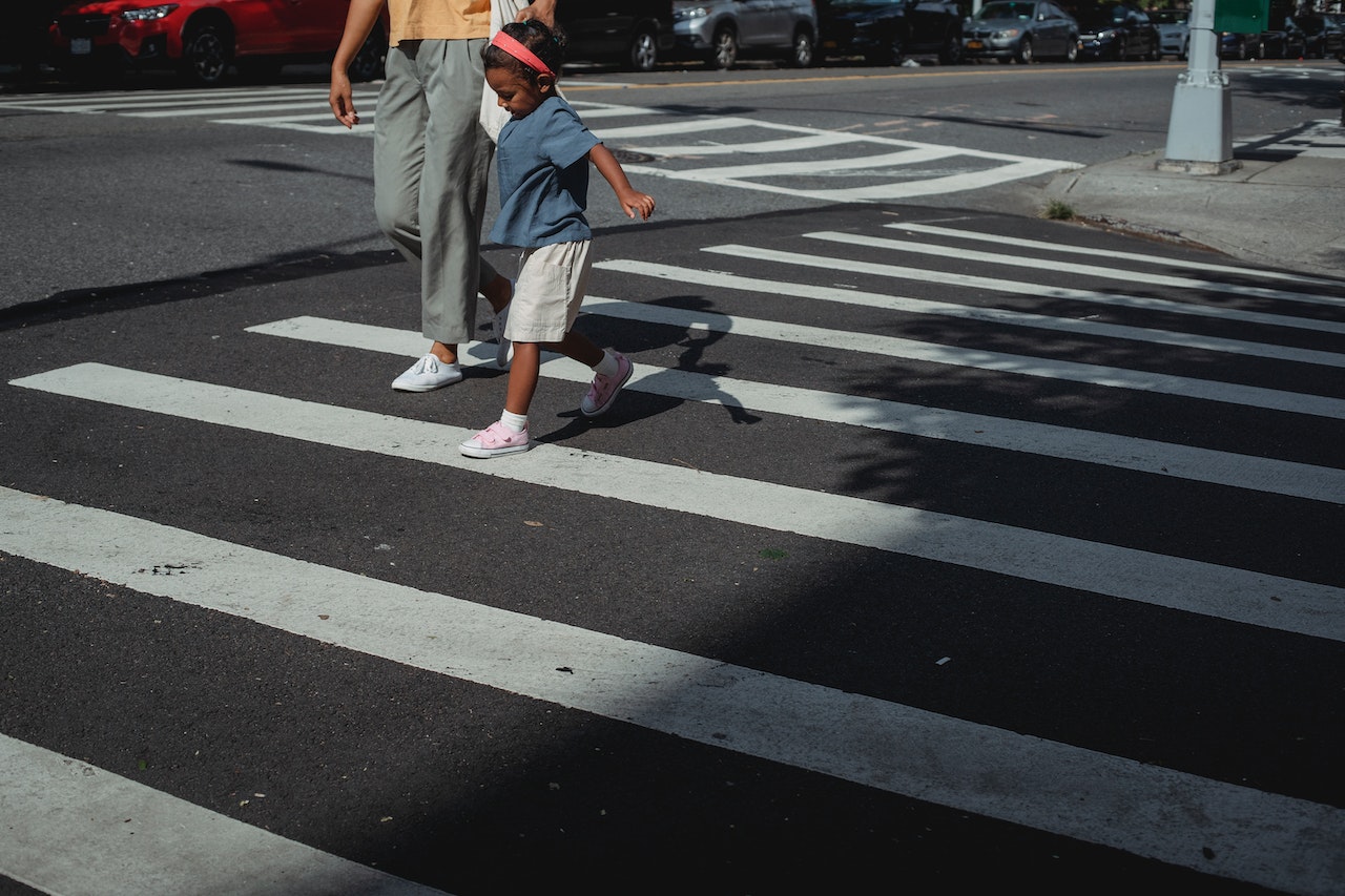 A child crossing the road with a parent