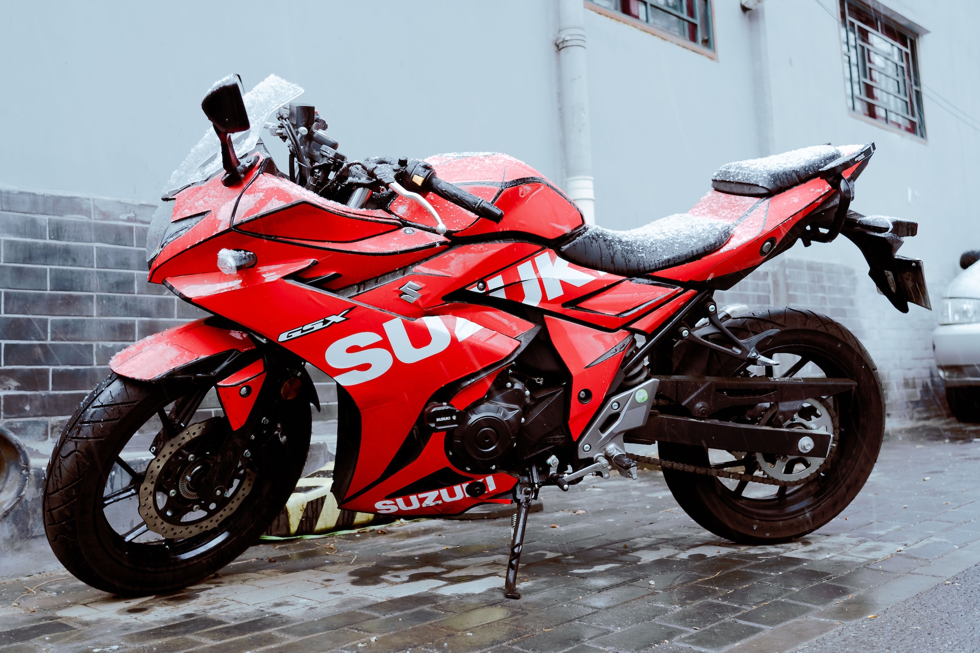 red suzuki parked in a snowy street