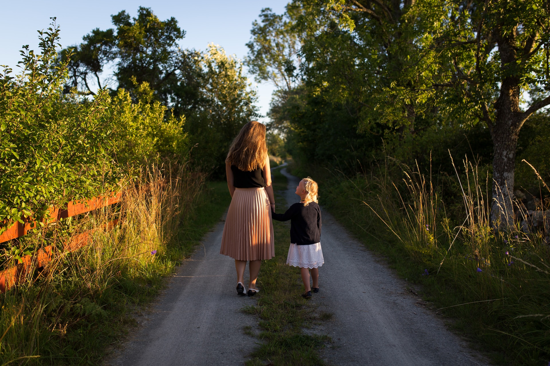 A child with their mother walking down a path