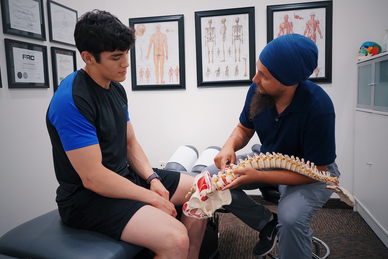 A doctor talking with a patient with a diagram of a spine