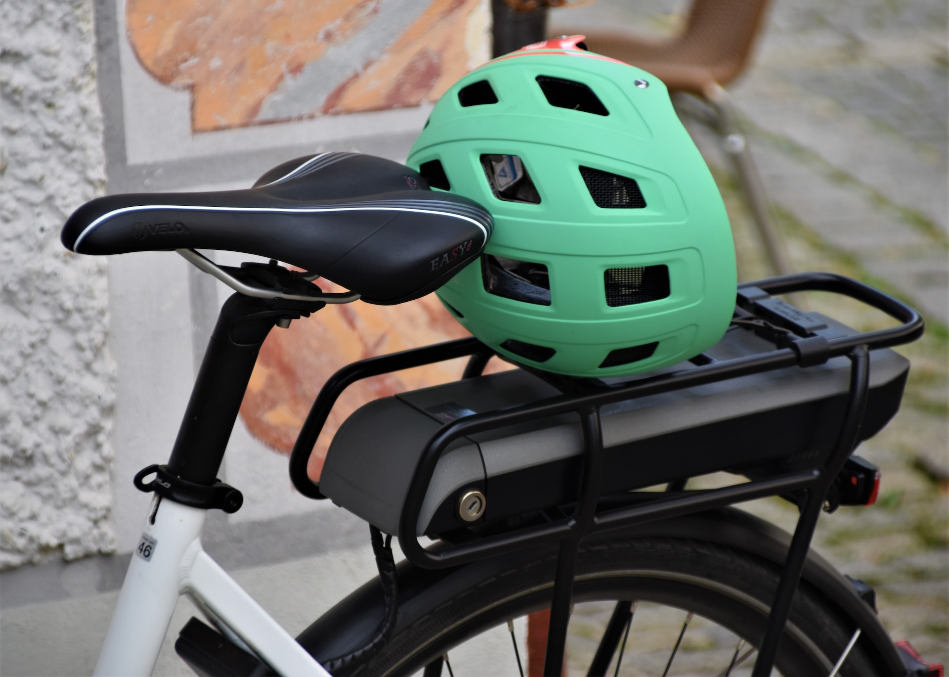 A green bicycle helmet resting on the back of a bicycle
