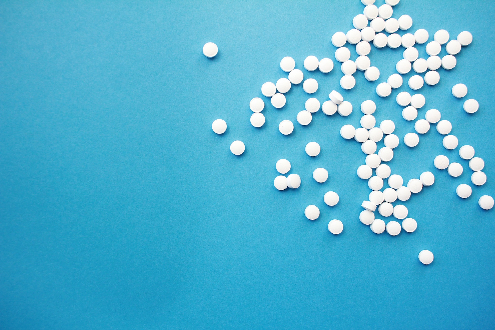 A number of white pills against a blue background