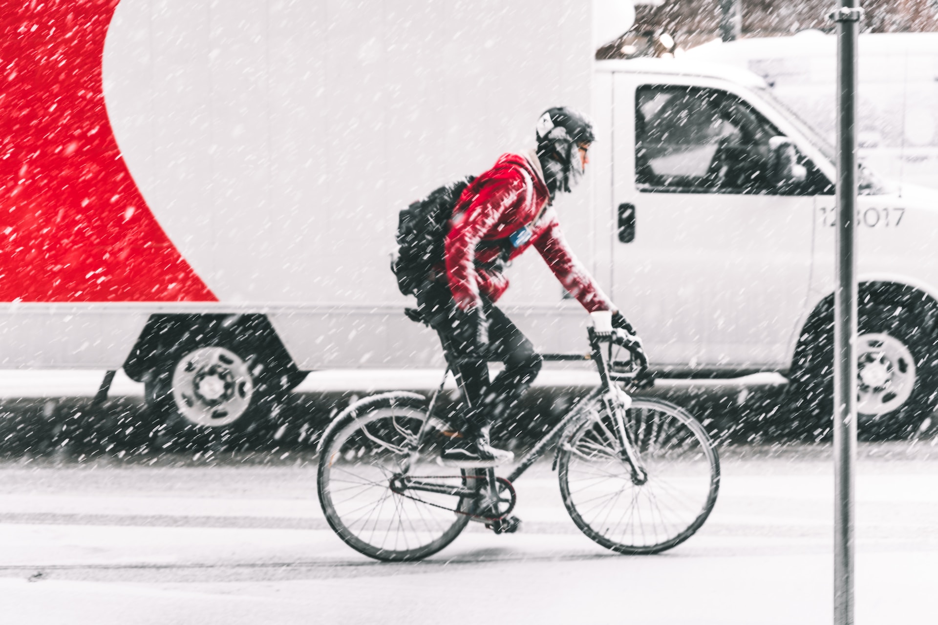 someone cycling in snow next to a van