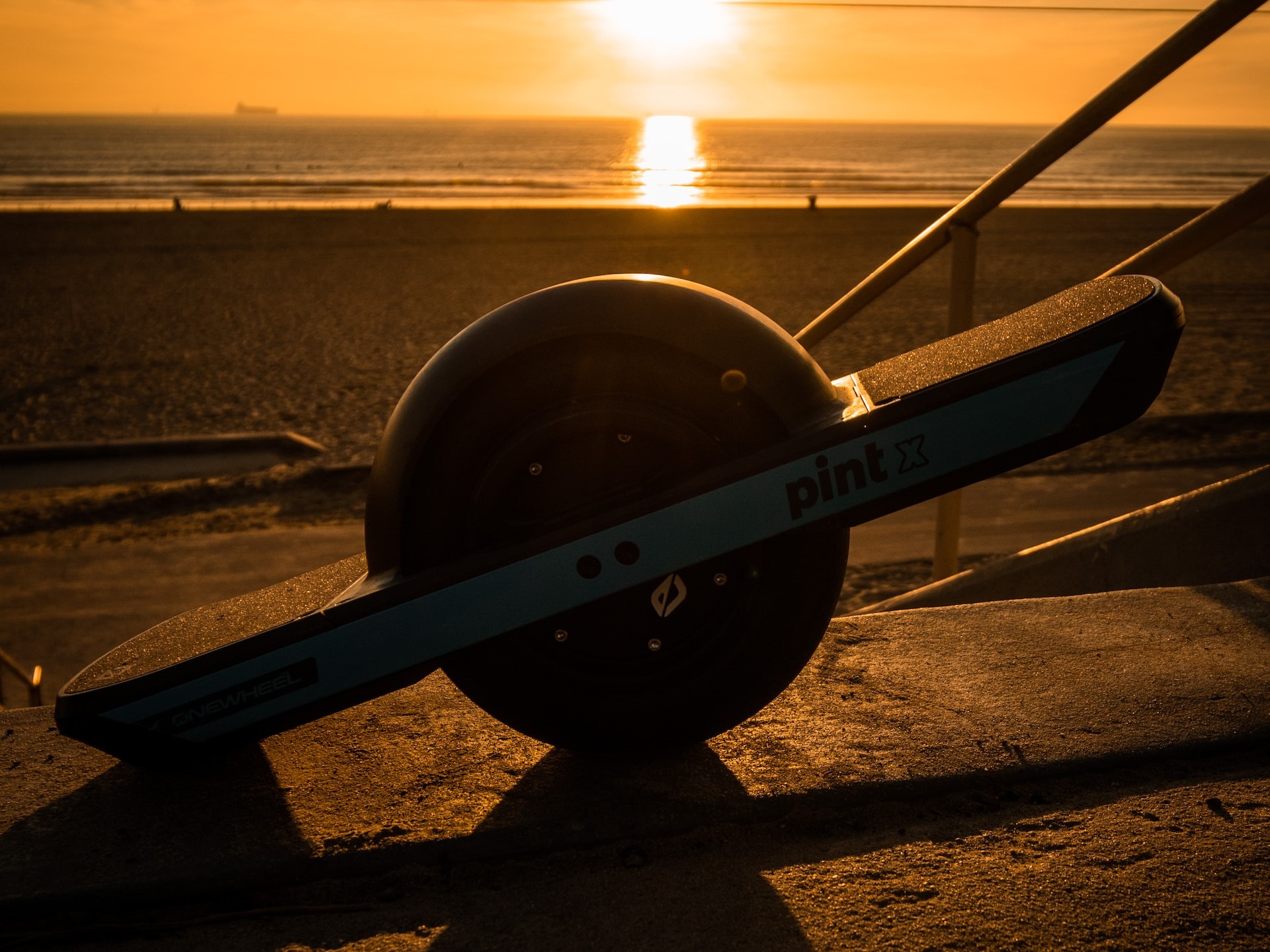 onewheel e skateboard with the sun setting in the background