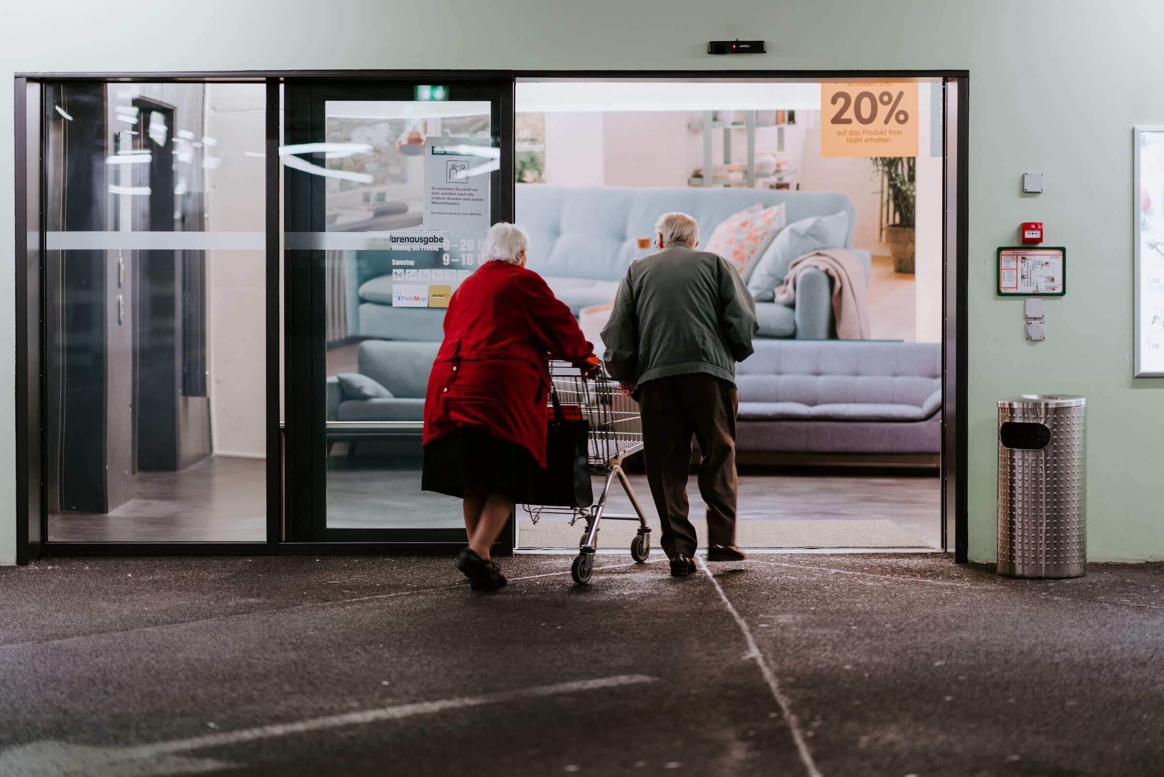 Two elderly people walking into a shop
