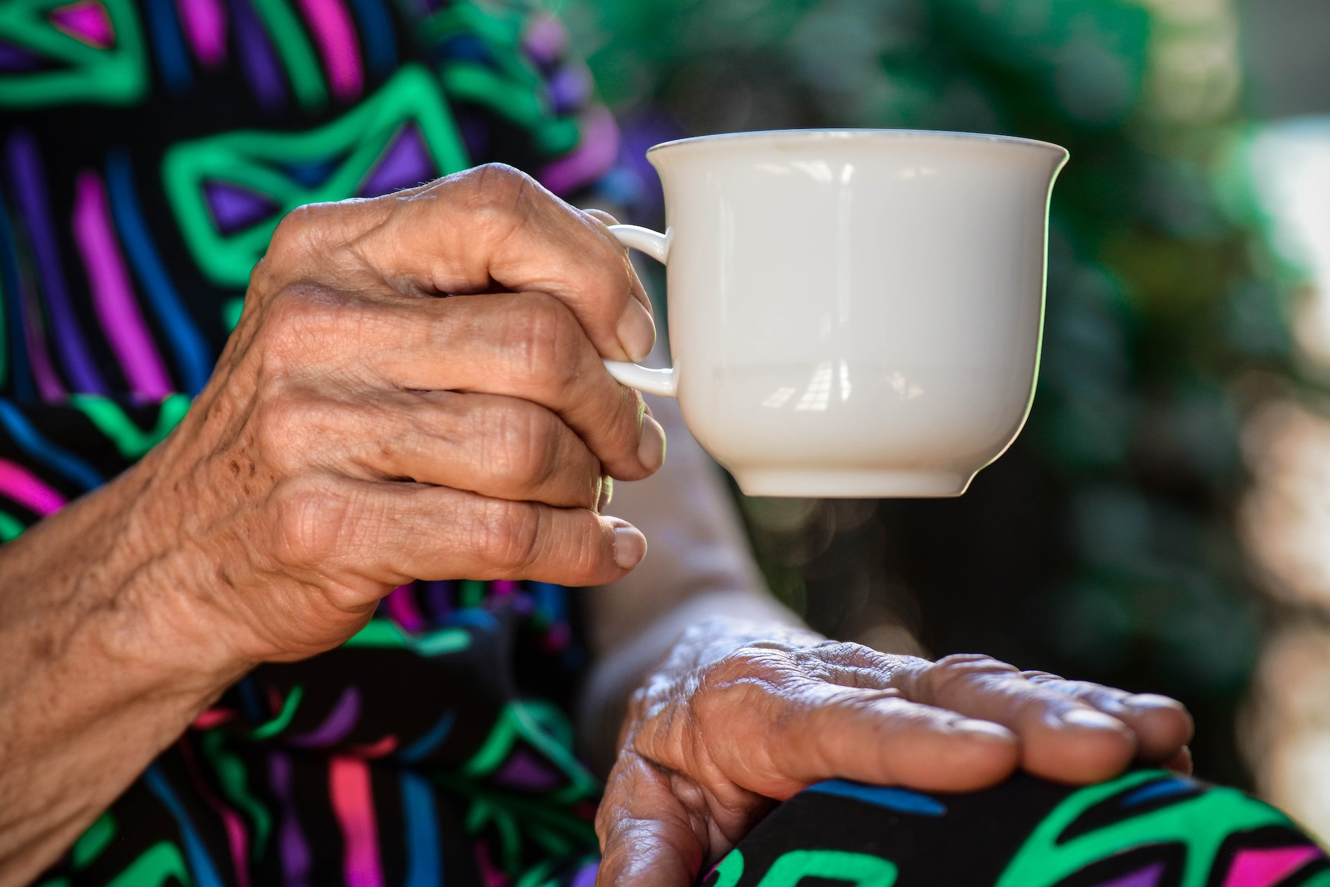 An elderly person with a mug in their hand