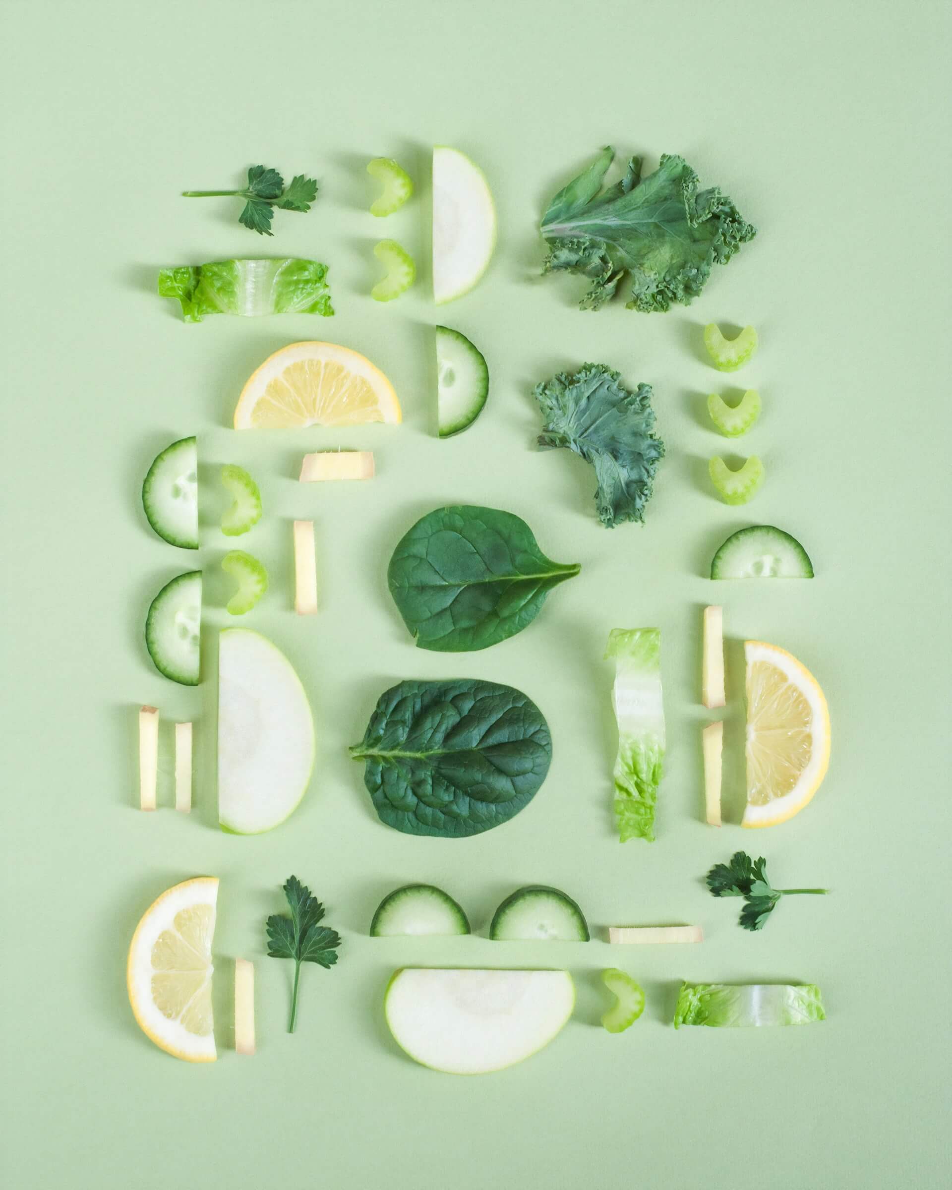Different fruits and vegetables sliced against a green background